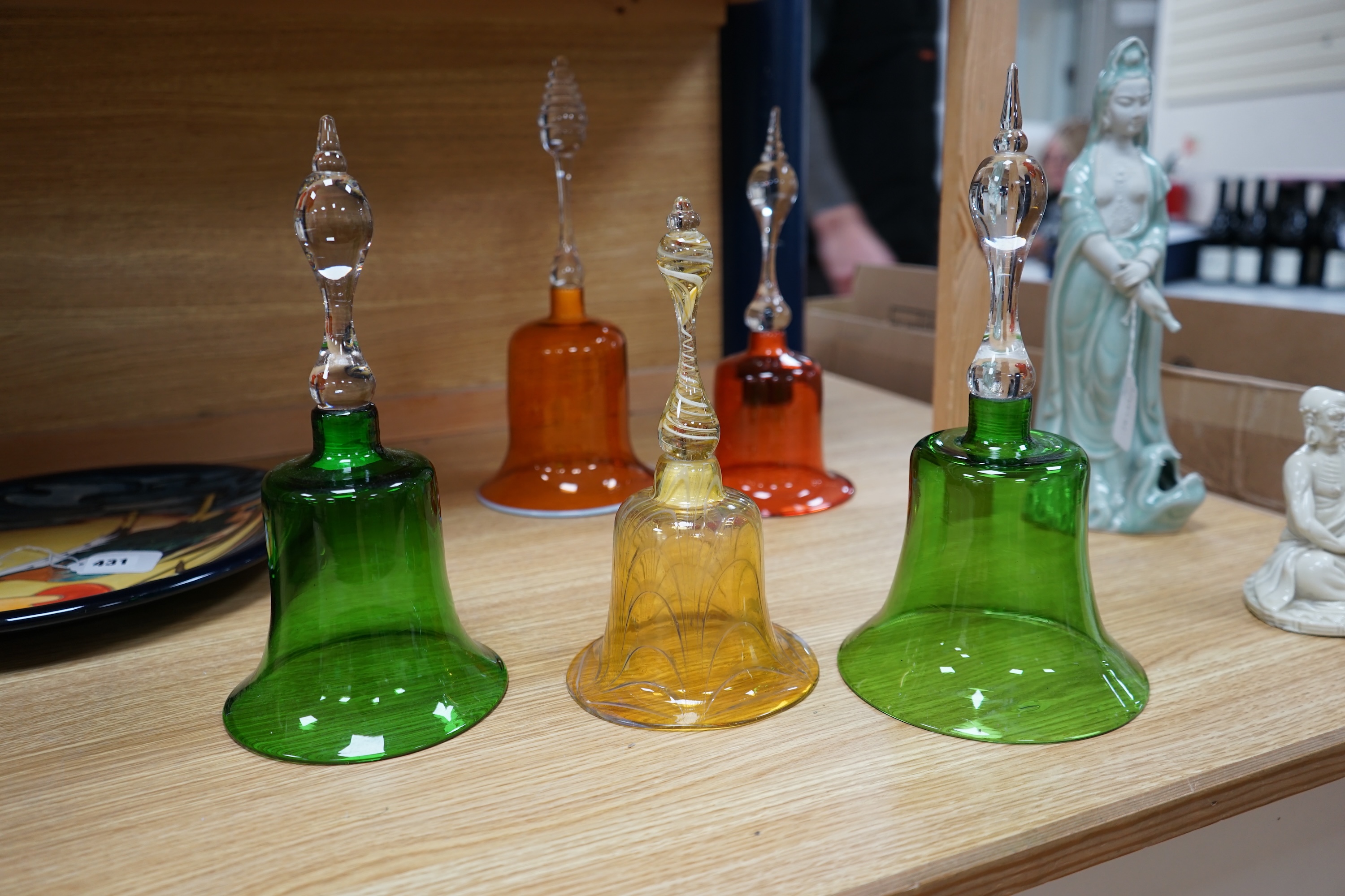 Five hand bells comprising an amber glass example with twist handle, two orange and two green glass hand bells, largest 36cm high. Condition - some repairs